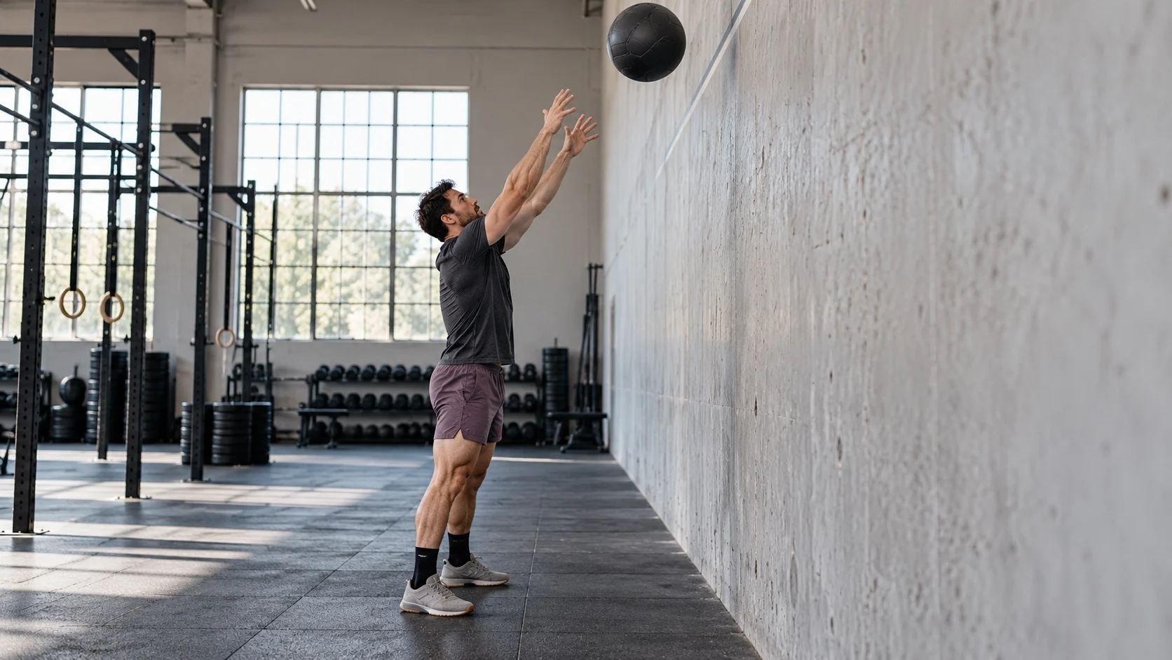 Athlète terminant un lancer de wall ball vers une cible murale.